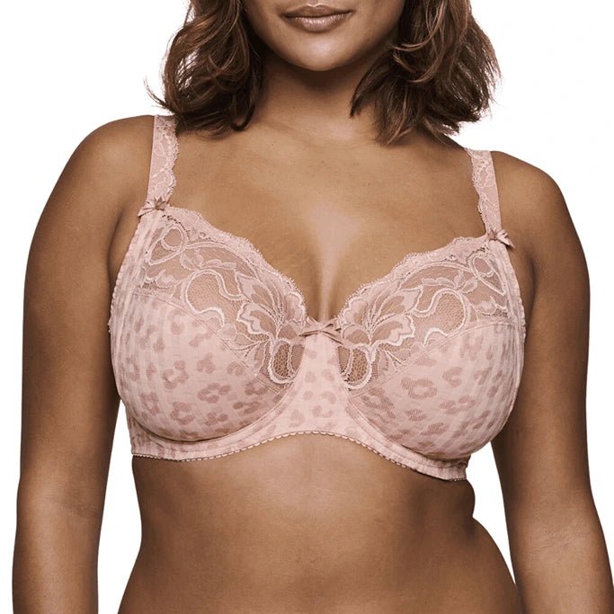 A close-up of a model wearing a light pink leopard-print lace bra with underwire and adjustable shoulder straps, shown against a plain white background.